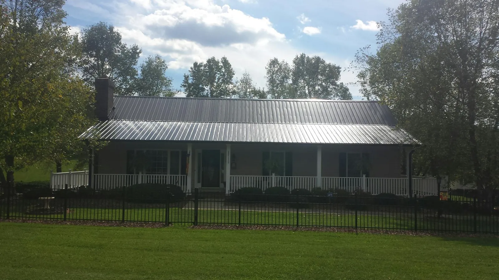 Gray metal roof on a brick ranch with a full width front porch — Gutter Guard Installation work by our crew in North Zulch