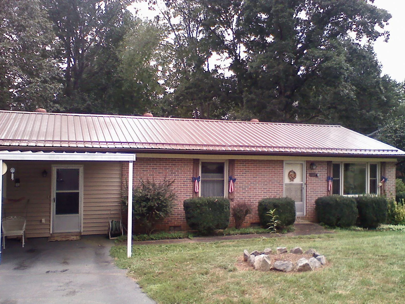 Bronze metal roof and carport on a brick ranch home — Roof Repair work by our crew in North Zulch