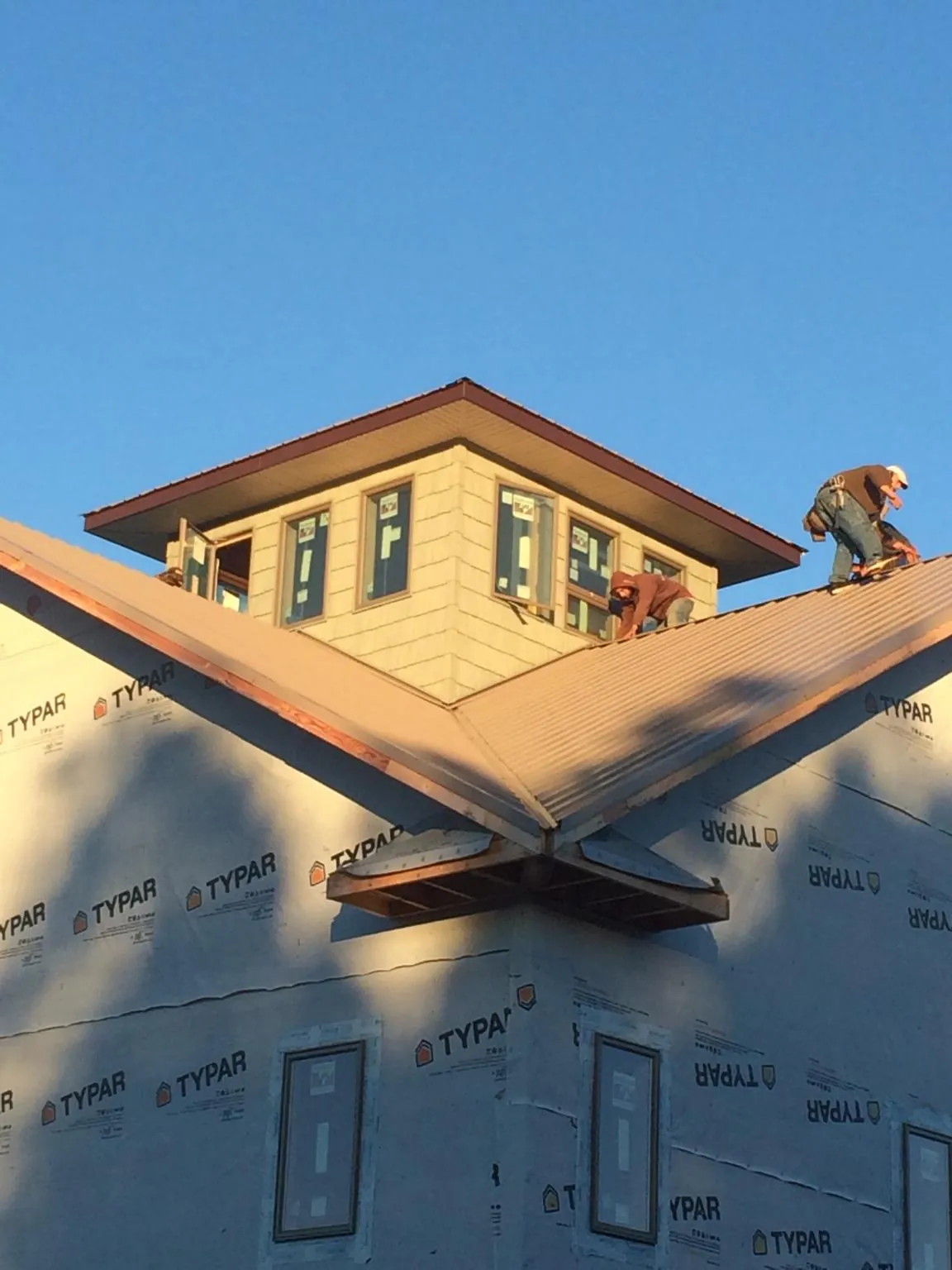 Roofers working around a rooftop cupola on a new metal roof at sunset — Roof Waterproofing in North Zulch by Roofing Brothers